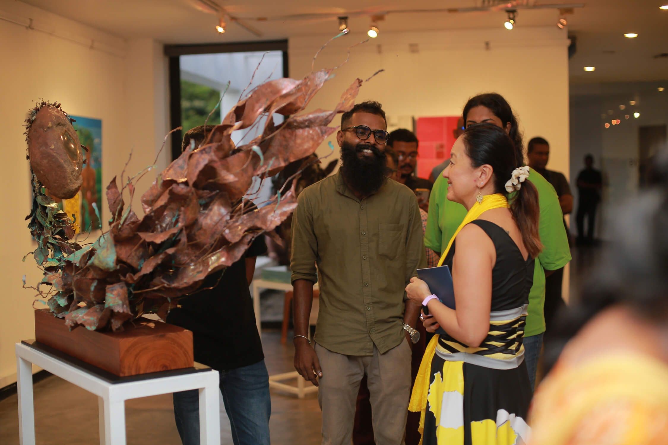 Julie J. Chung, the United States Ambassador to Sri Lanka, engaging with Dimal Madusanka while admiring his artwork at the Danery Odyssey exhibition.